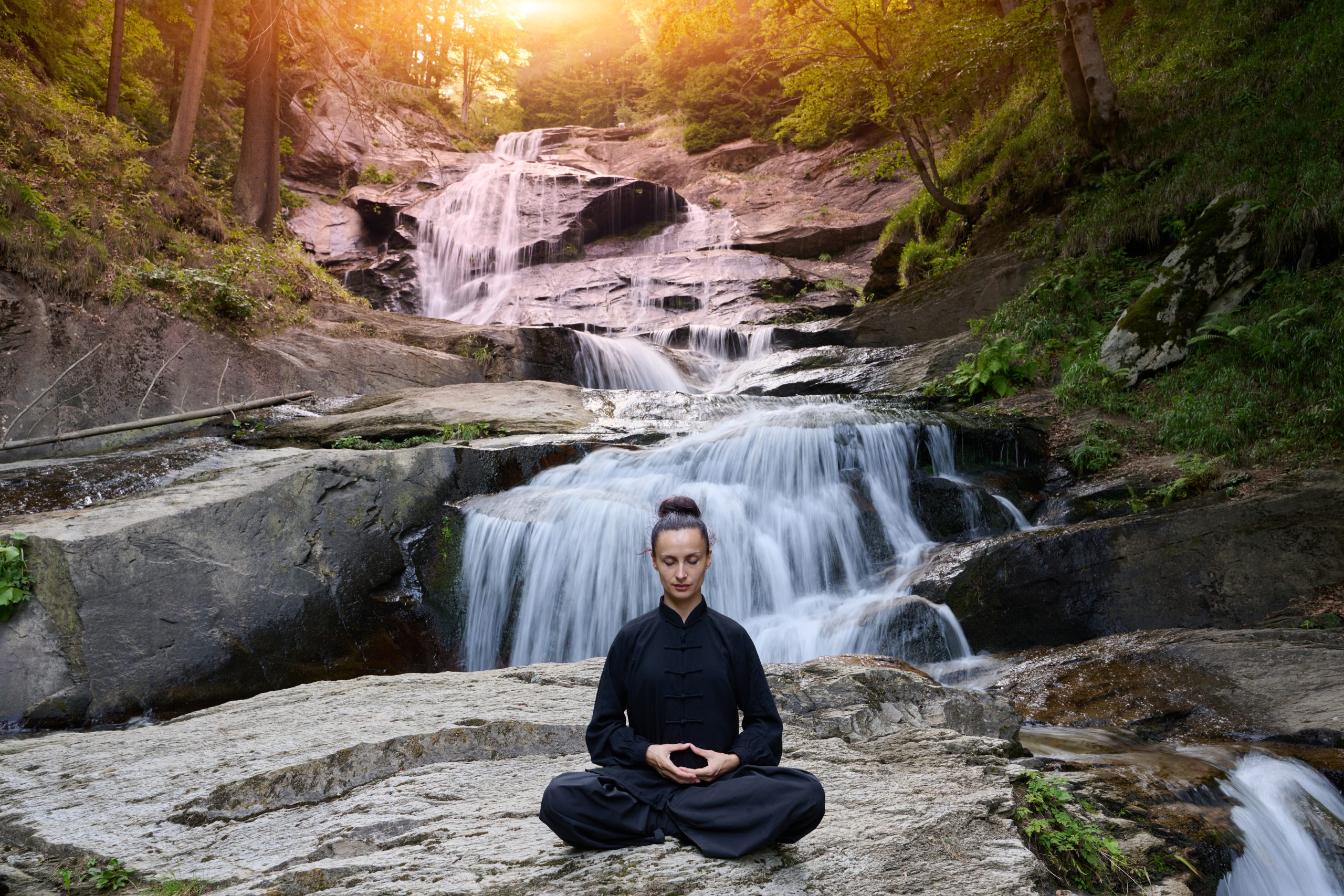 A woman sits in lotus pose, practicing yoga and tai chi under a tropical waterfall, meditating with calm strength and mindfulness, fully connected to the energy of nature, tranquility and inner balance.